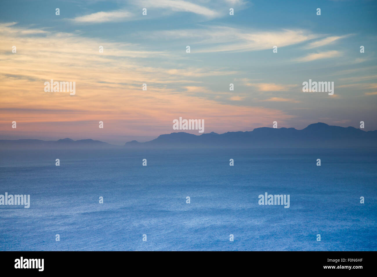 The Indian ocean and a mountain range, shrouded in mist, with silhouettes against the sky. Cape Point in South Africa. Stock Photo