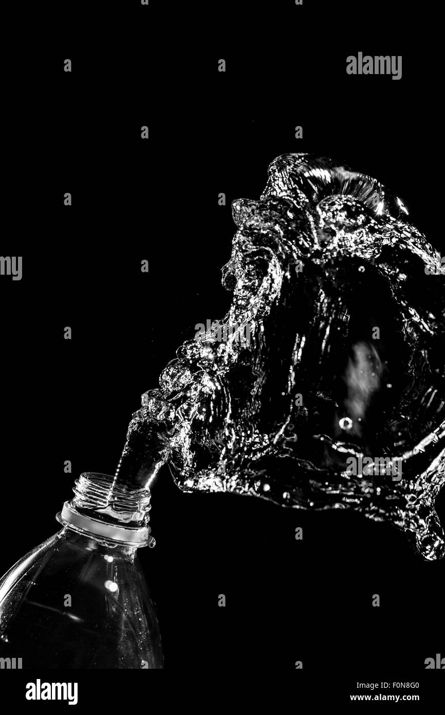 Abstract water jet crashes on a black background from a plastic bottle