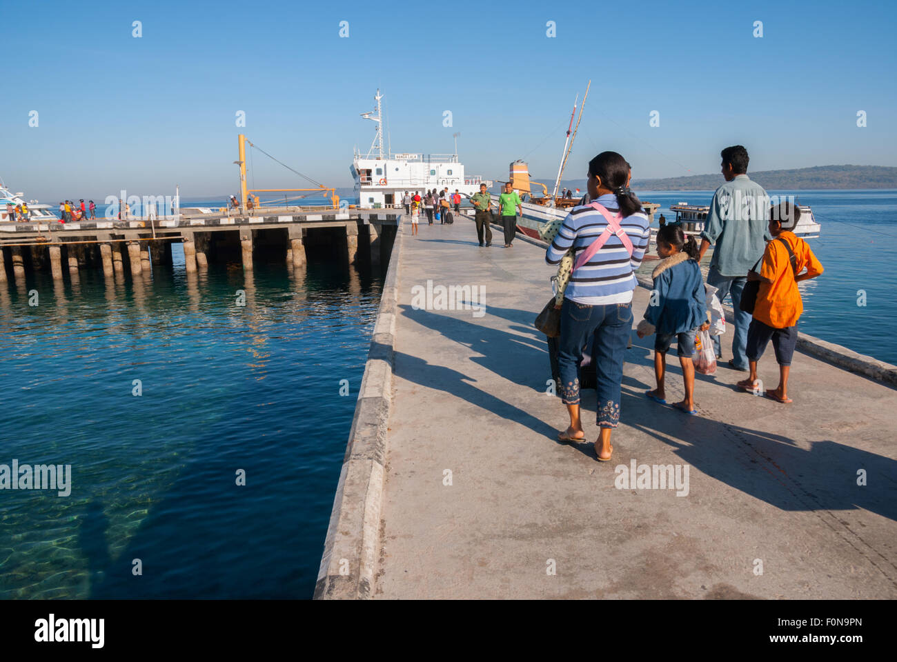 A family walking on jetty toward ferry boat at ferry harbour in Kupang, East Nusa Tenggara, Indonesia. Stock Photo