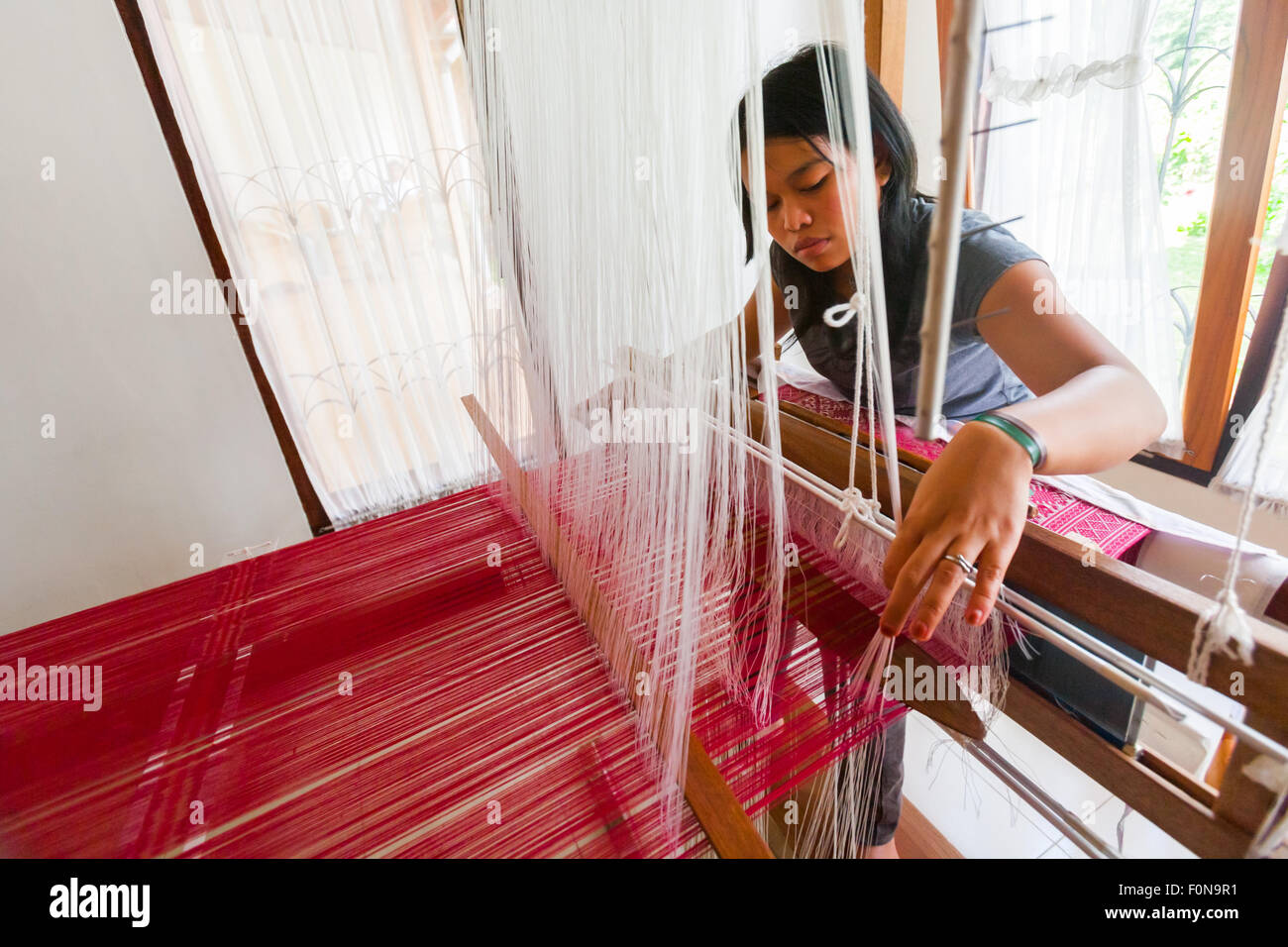 A woman making songket fabric at Erika Rianti songket studio in Bukittinggi, West Sumatra, Indonesia. Stock Photo