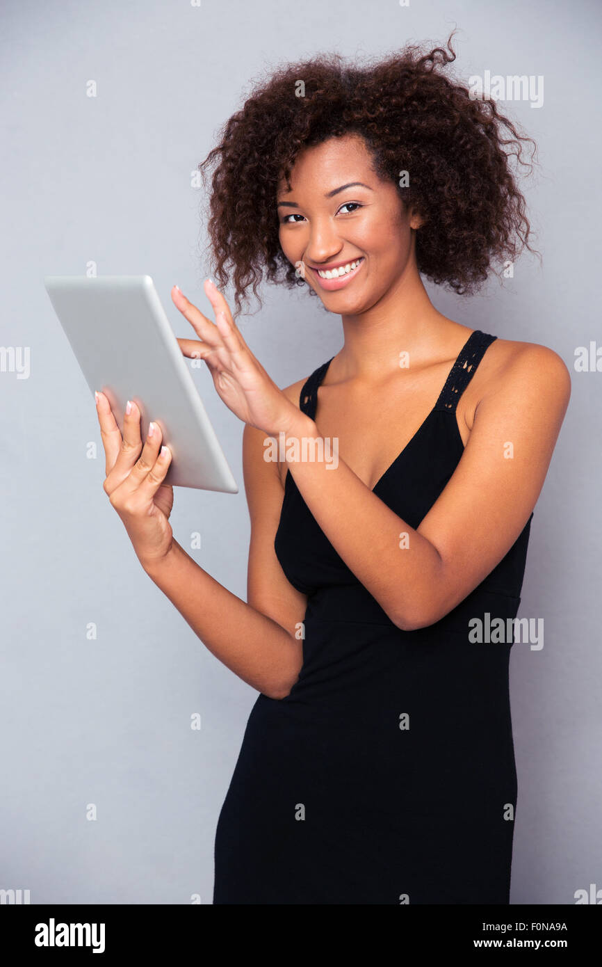 Portrait of a smiling african woman using tablet computer over gray ...