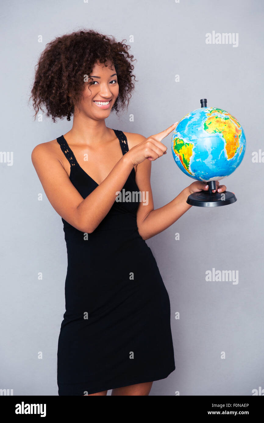 Portrait of a happy african woman holding globe over gray background Stock Photo