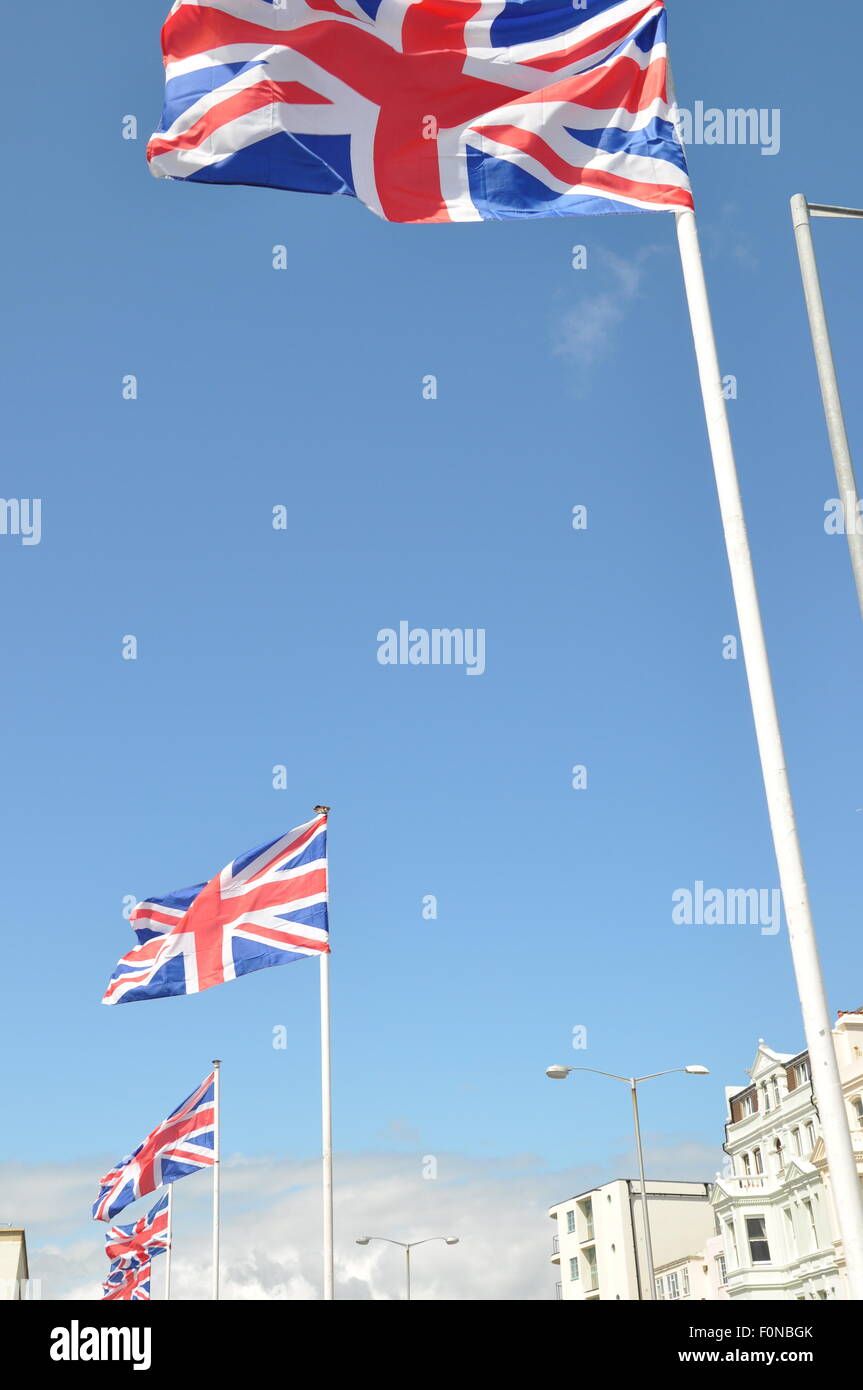 Union jack flag flying in the wind against a blue sky Stock Photo - Alamy