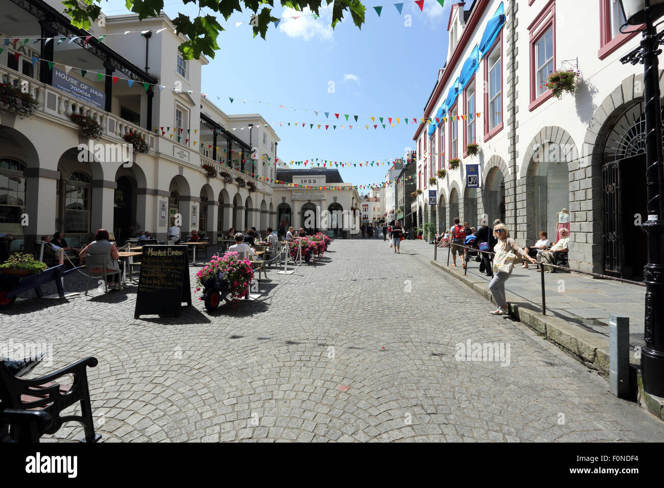 Market square in St. Peter Port, Guernsey. It is a sunny day, and people are sitting outside at cafés, and walking along. Stock Photo