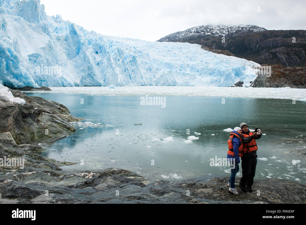 Young couple taking a selfie in front of Brujo Glacier Asia Fjord Patagonia Chile Stock Photo
