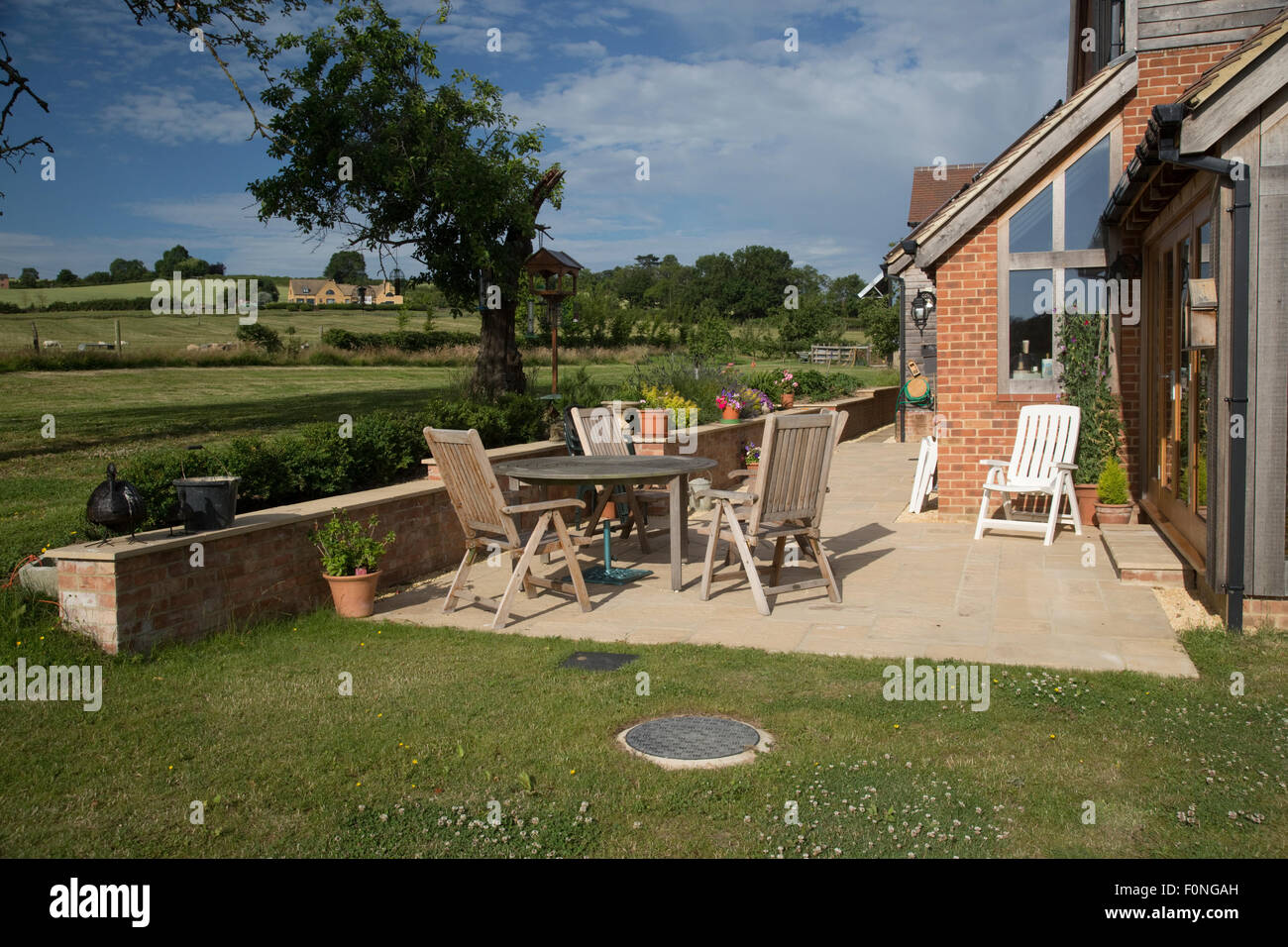 Empty teak chairs and table on patio of new ecohouse UK Stock Photo