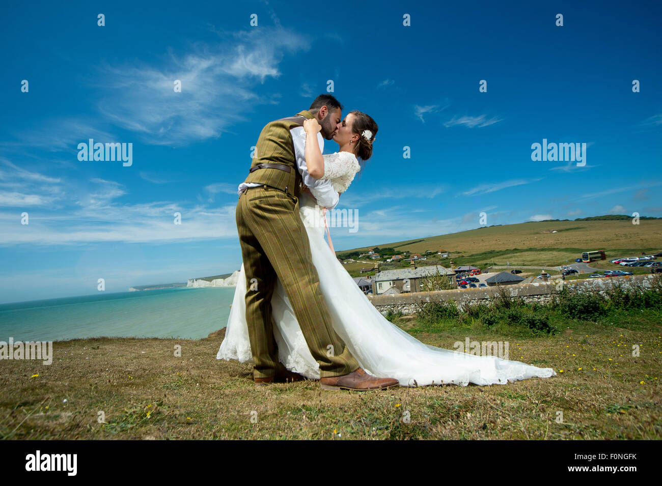 A couple share a romantic kiss on their wedding day at birling gap, East Sussex, UK. Stock Photo