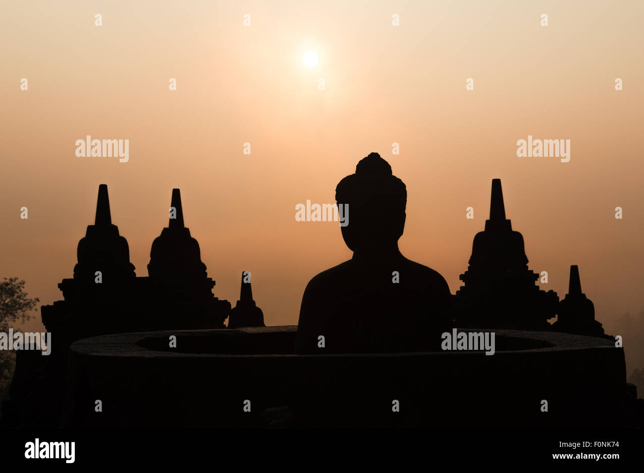 Silhouettes of a buddha statue at the Unesco world heritage site the Borobudur temple at dawn on the island of Java, Indonesia, Asia. Stock Photo