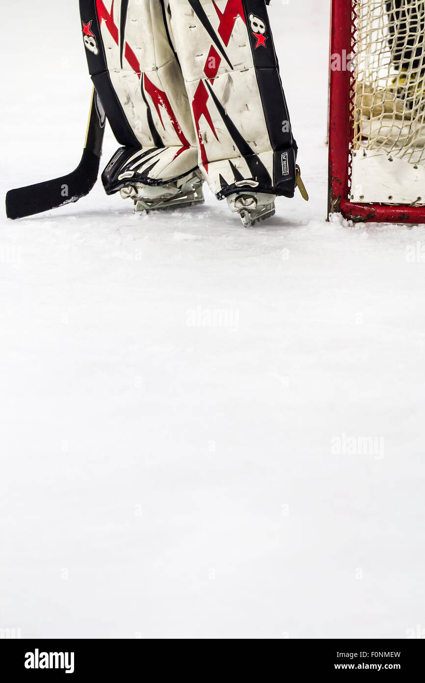 Ice hockey goalkeeper standing next to the goal on ice. Stock Photo