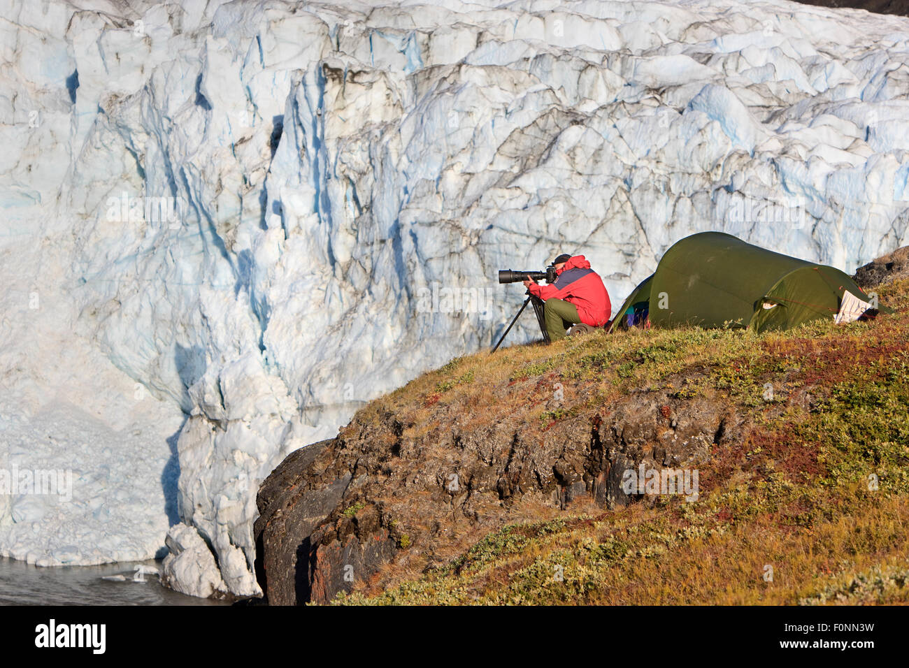Photographer, Kai Jensen, sitting outside tent photographing, by the Russells glacier, Greenland, August 2009 Stock Photo