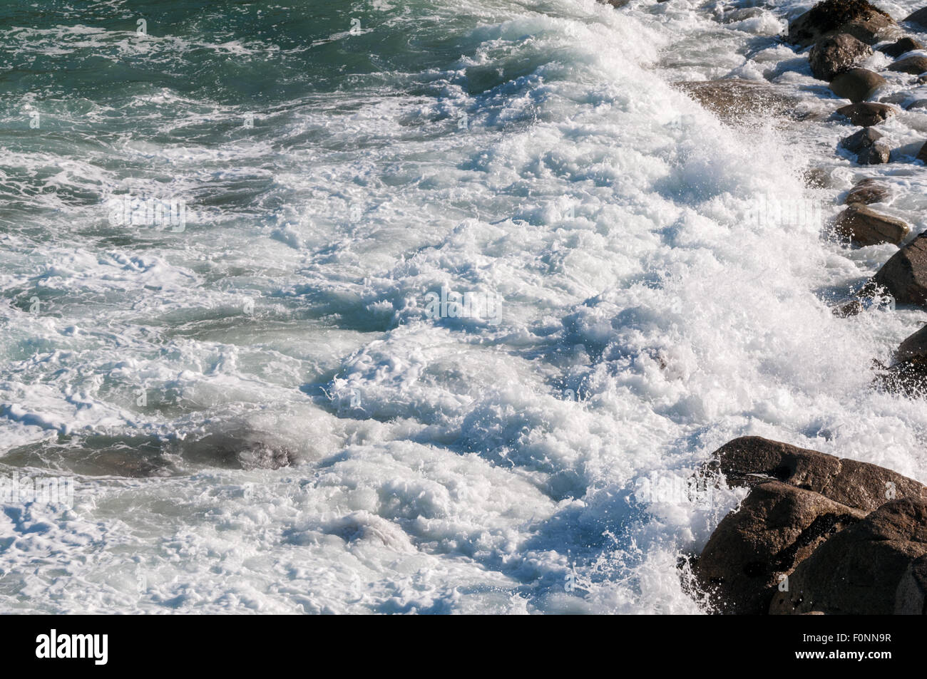 Close up detail shot of waves crashing against rocks Stock Photo