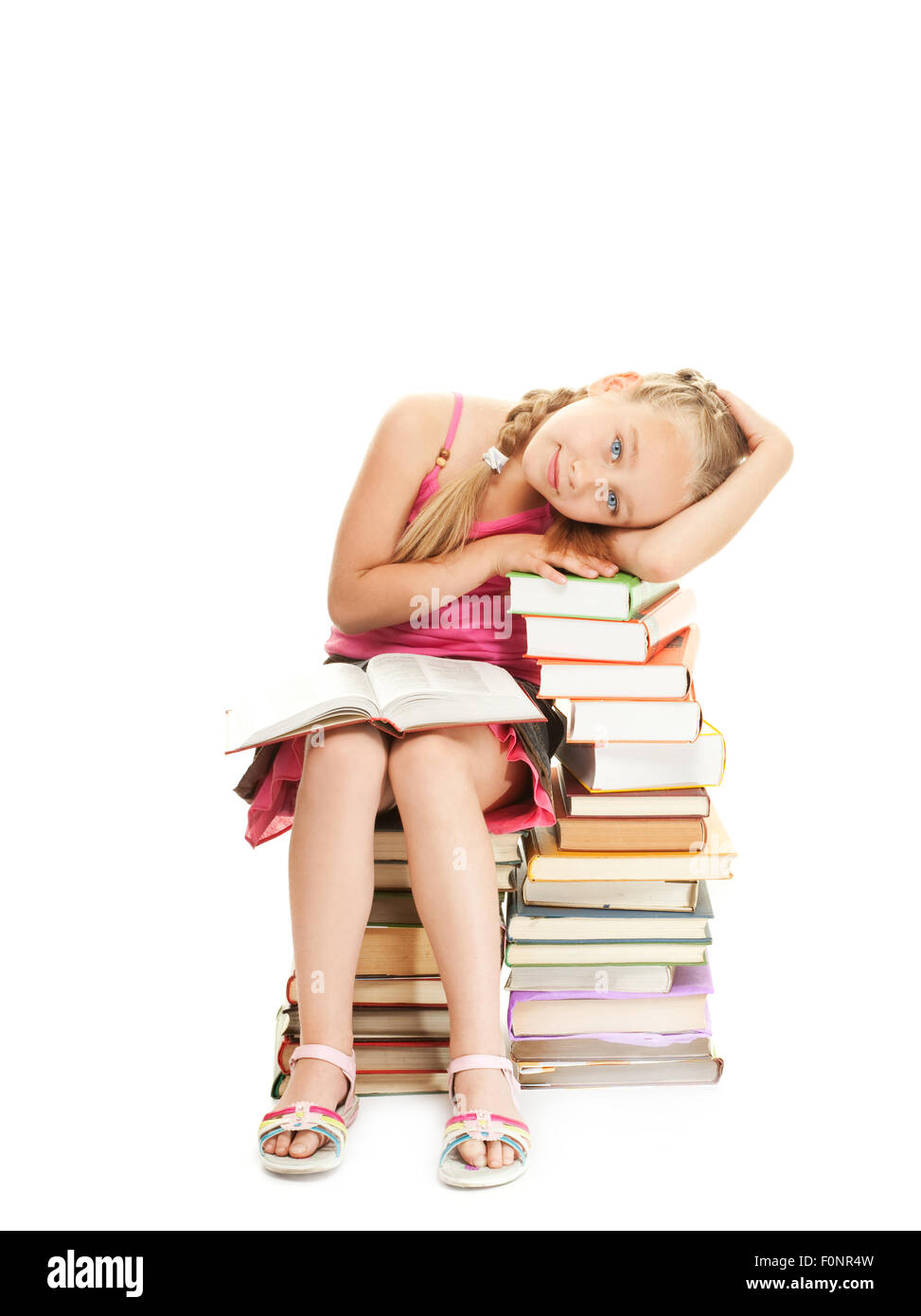 Little schoolgirl sitting on a stack of books Stock Photo - Alamy