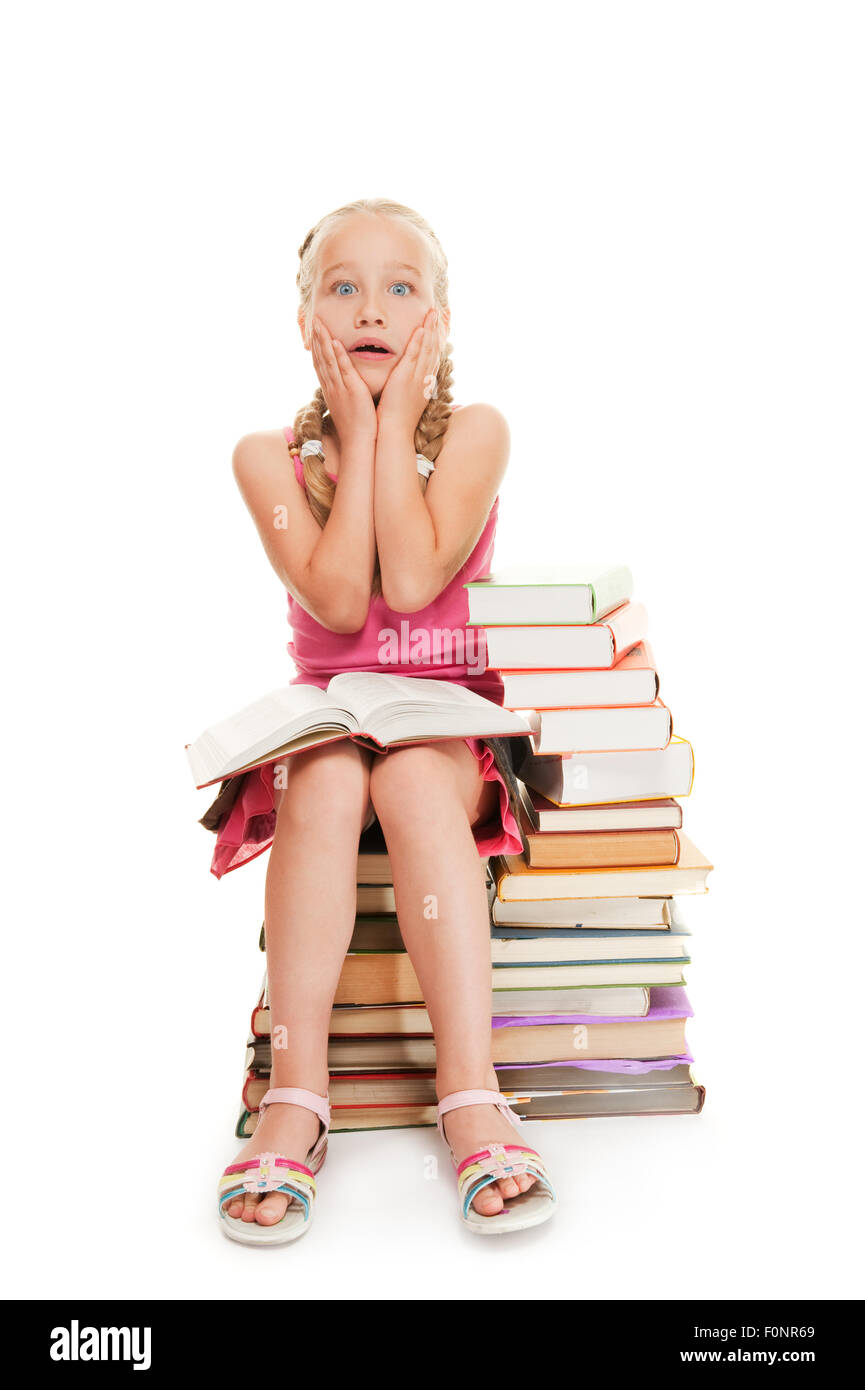 Little schoolgirl sitting on a stack of books Stock Photo - Alamy