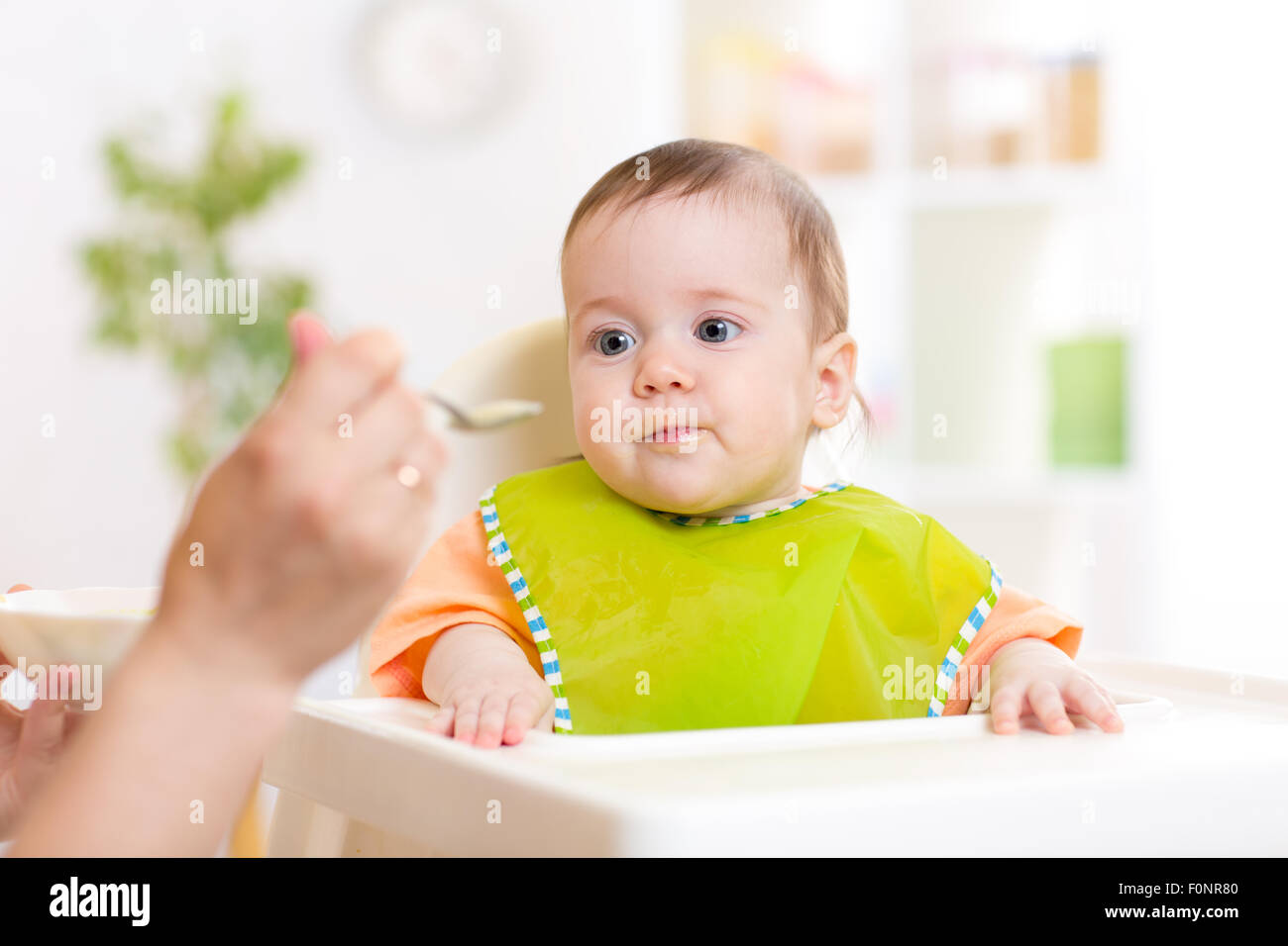 Mom feeding baby with spoon Stock Photo