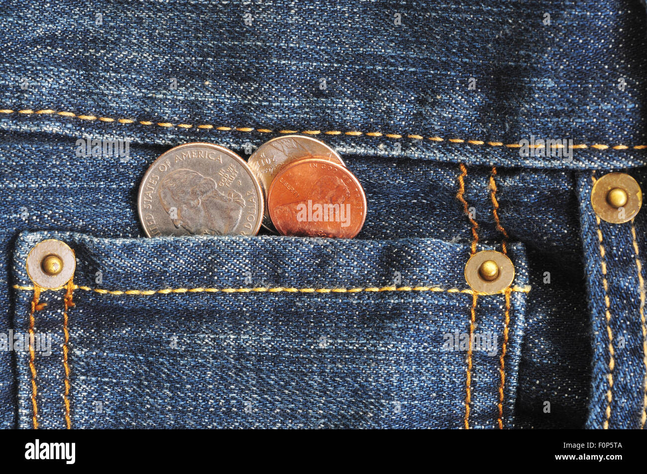 Macro shot of a jean's pocket with coins coming out of it Stock Photo