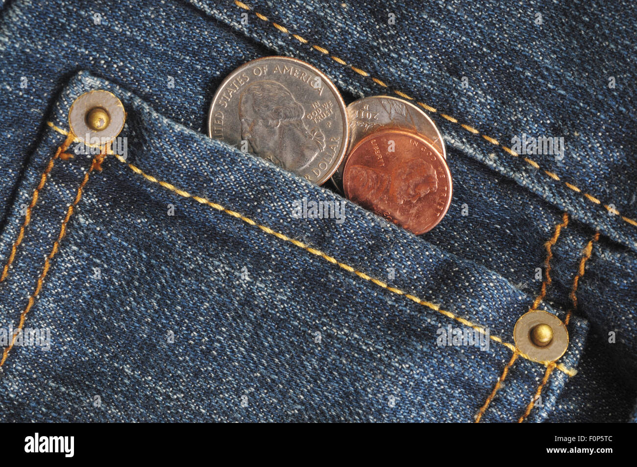 Macro shot of a jean's pocket with coins coming out of it Stock Photo