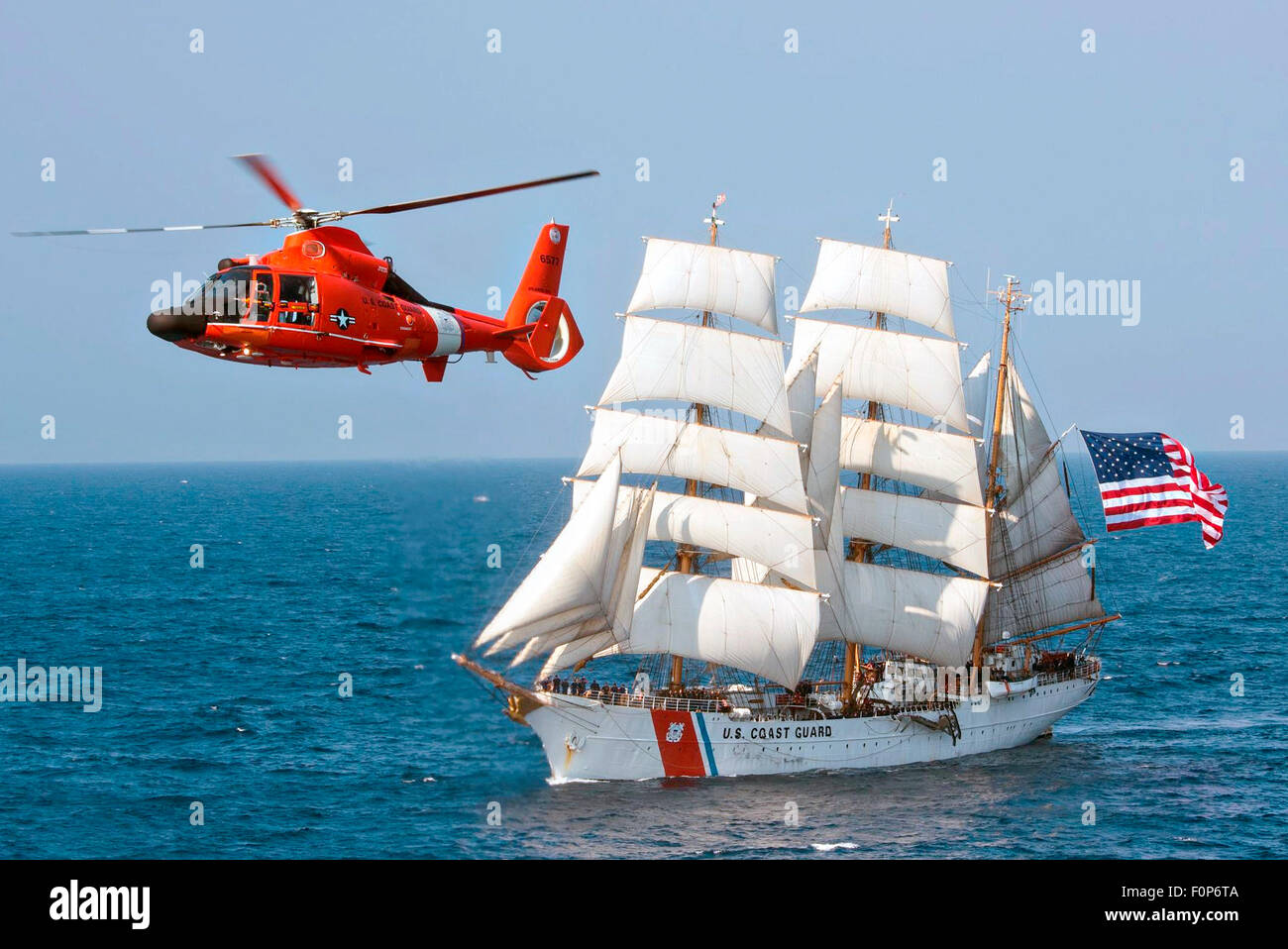 The Coast Guard cutter Eagle sails in the Atlantic Ocean followed by a MH-65 Dolphin helicopter July 30, 2015. The barque Eagle is the only active commissioned sailing vessel in American military service. Stock Photo