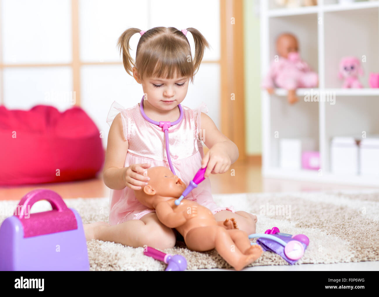 cute little girl playing with doll at home Stock Photo