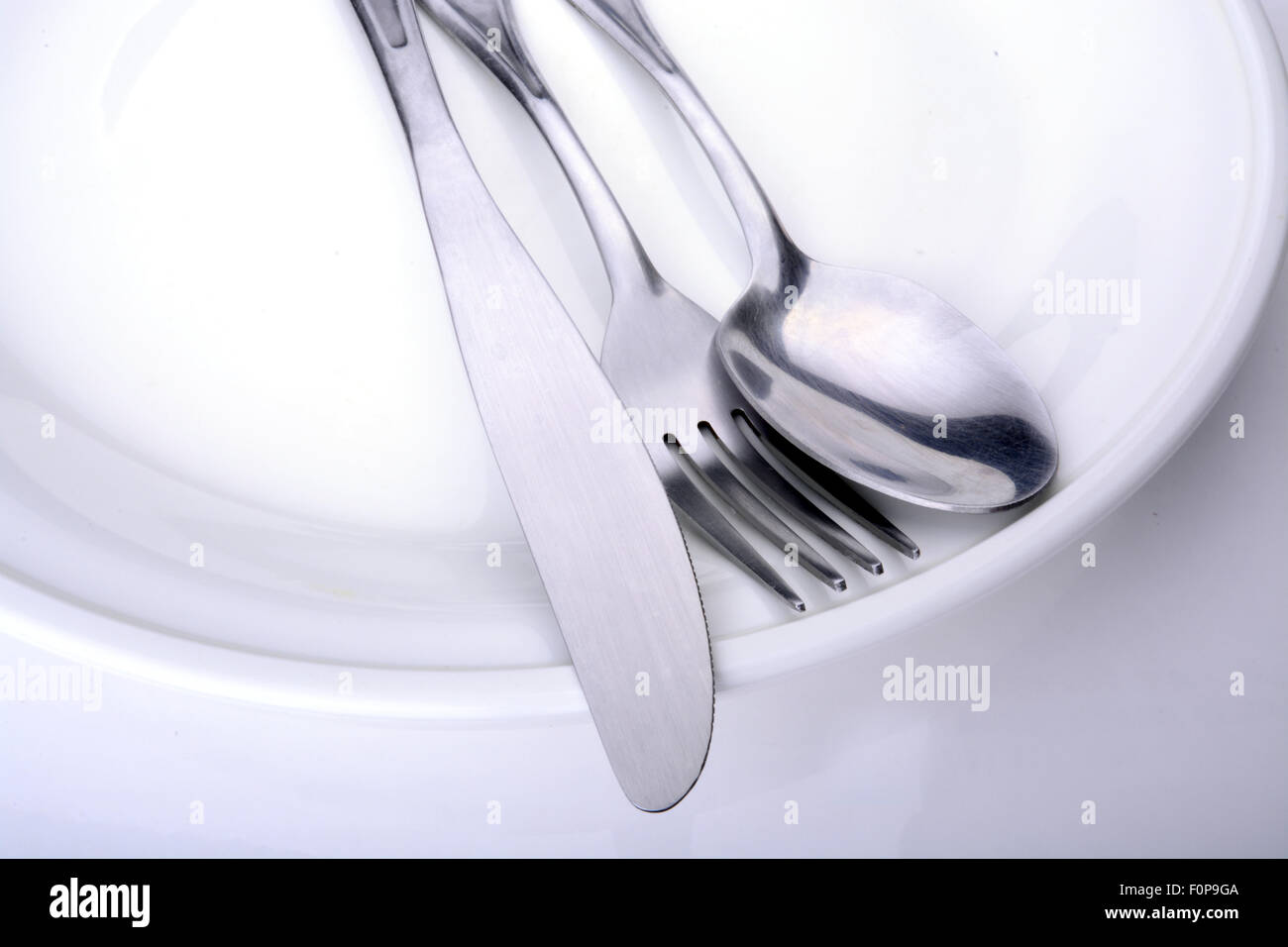 Macro shot of a white plate with utensils on it Stock Photo