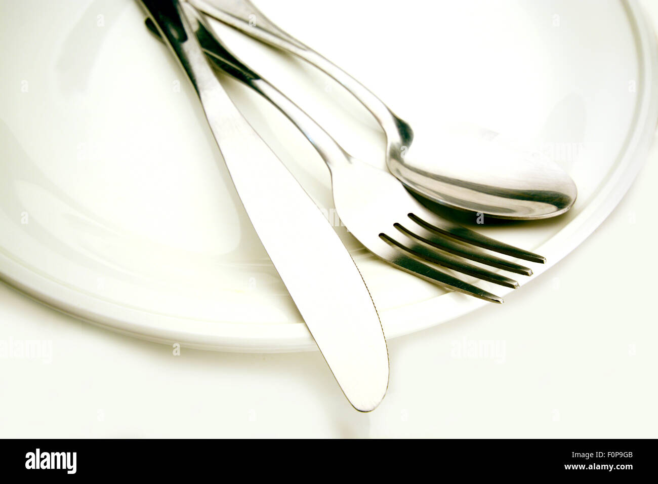 Macro shot of silverware over a white plate Stock Photo