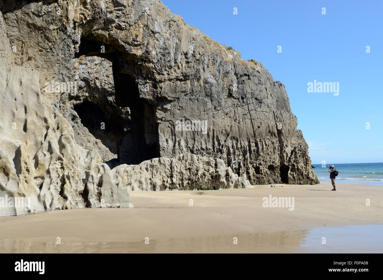 man standing on the beach taking a photograph of Lydstep Caverns Pembrokeshire Coast National Park Wales Cymru UK GB Stock Photo