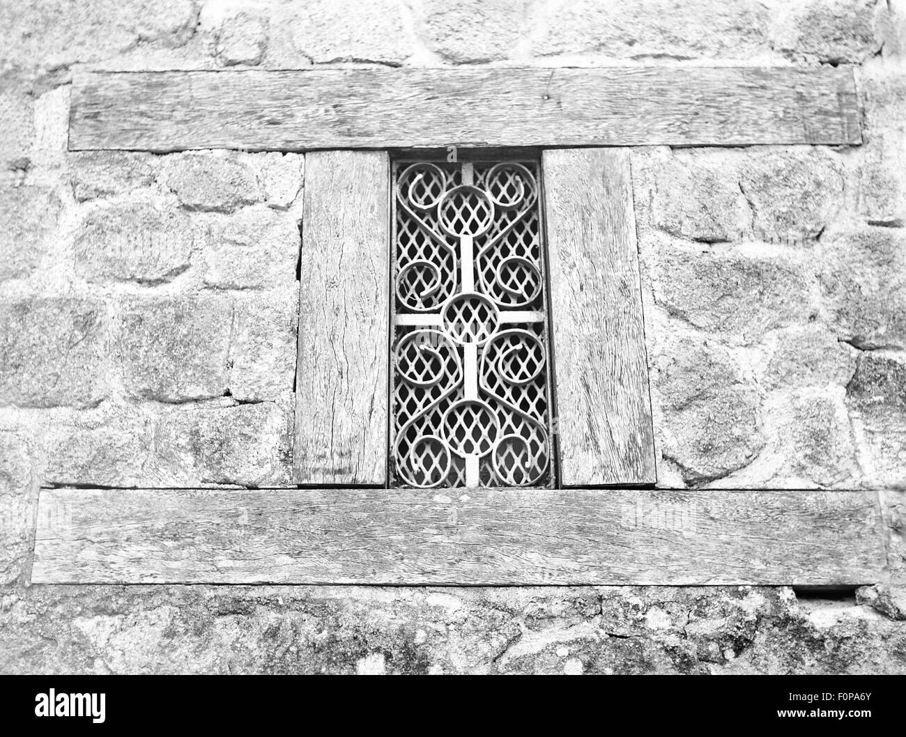 Old stone wall with a wooden frame and small welded iron window in ...