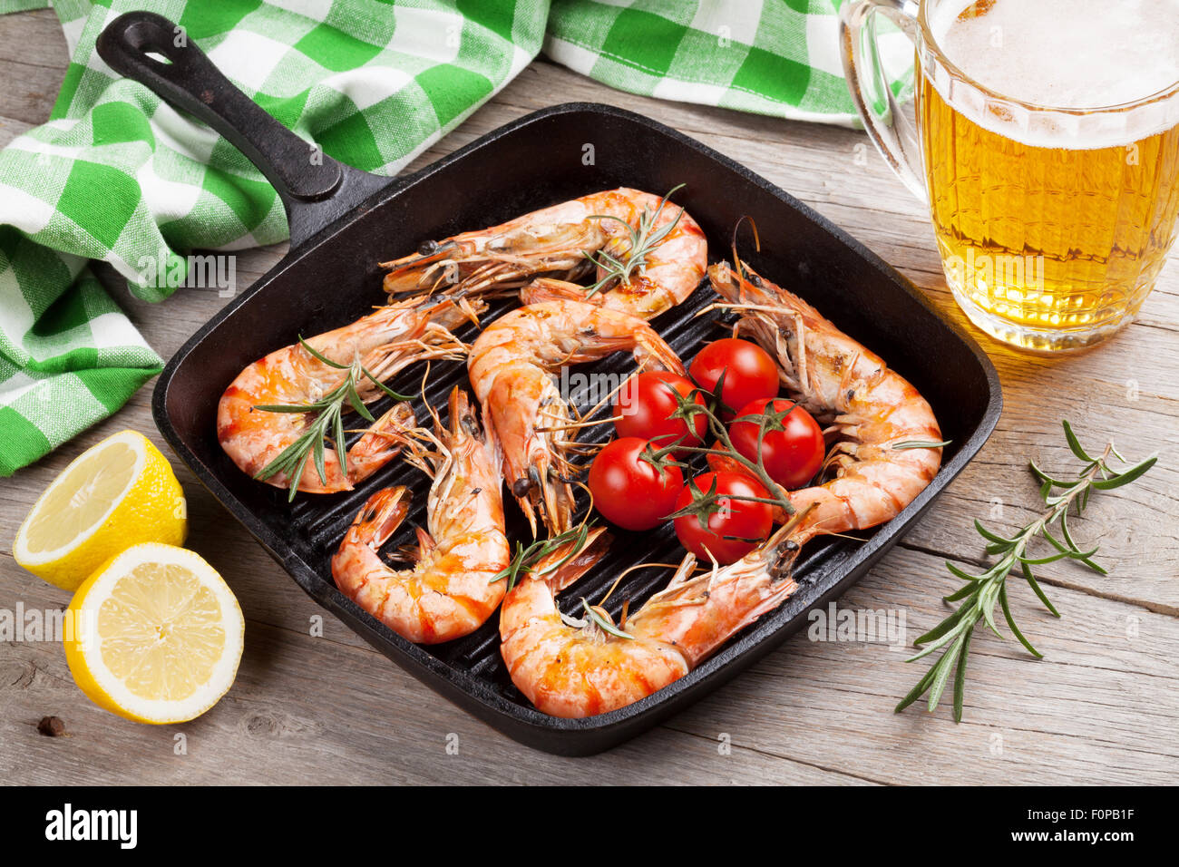 Grilled shrimps on frying pan and beer on wooden table Stock Photo