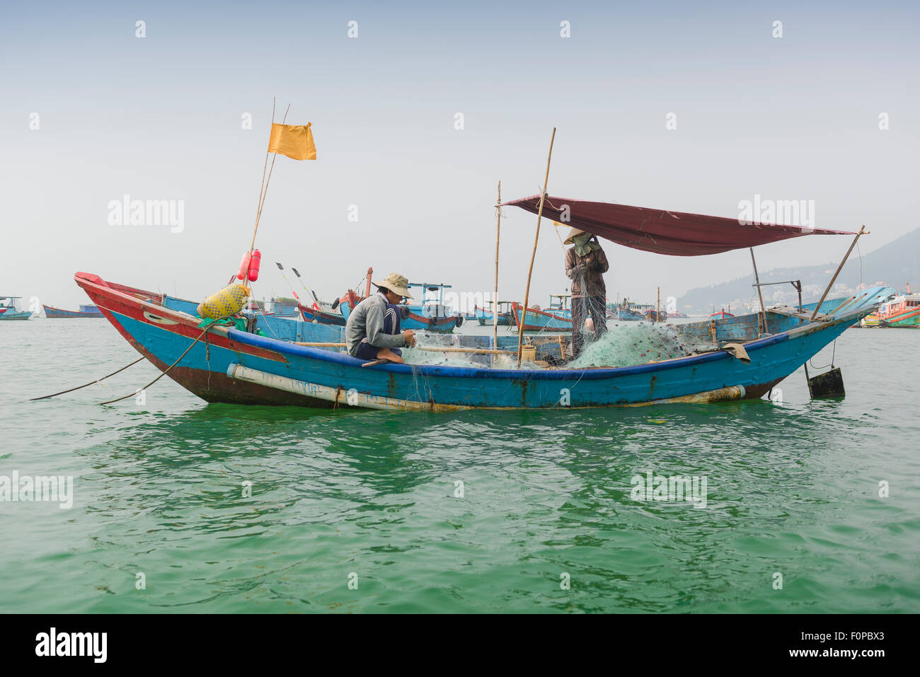 Vietnam boat, Vietnamese fishermen mend nets onboard a fishing boat at