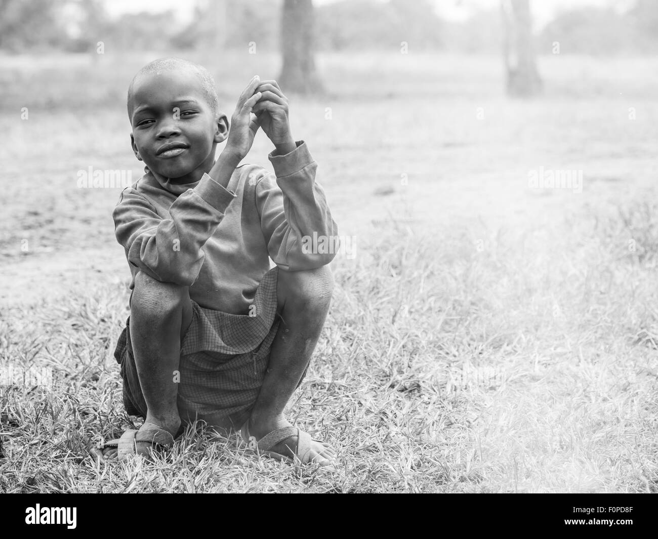 Maasai child sitting next to a fire in his boma (village) in Tanzania, Africa. Stock Photo
