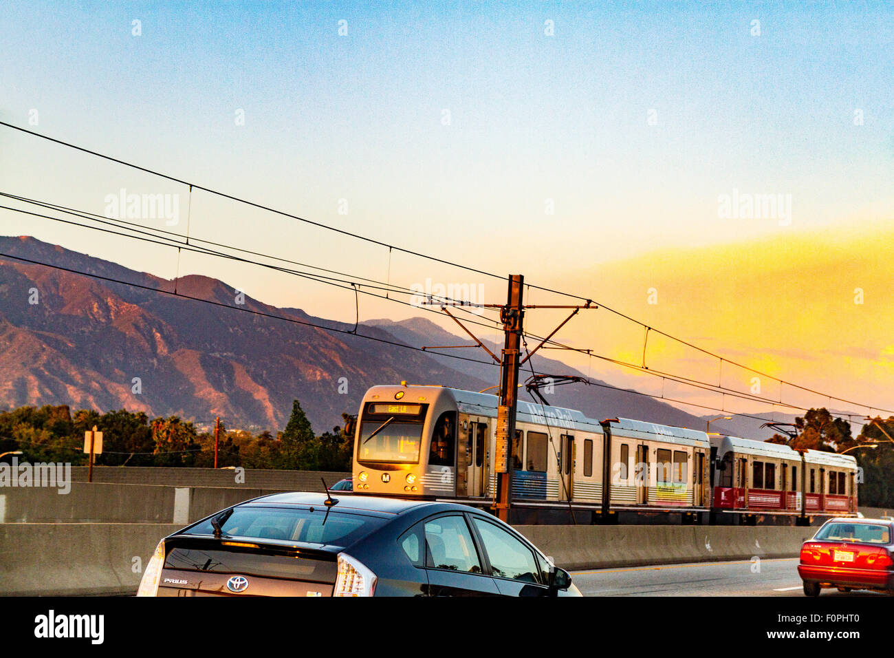 A Los Angeles Metro Rail train along the 210 freeway near Pasadena California in the golden light of sunset. Stock Photo