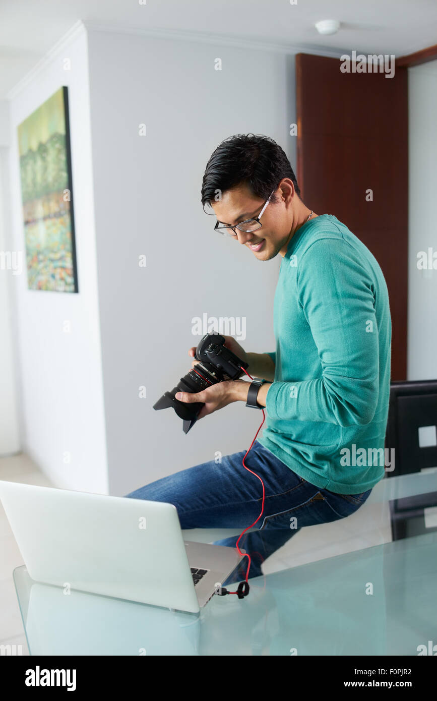 Chinese man connecting digital dslr camera to laptop computer via USB
