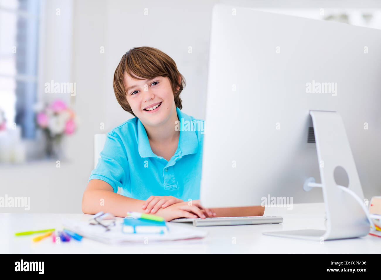 School boy working on personal computer at home. Student doing homework