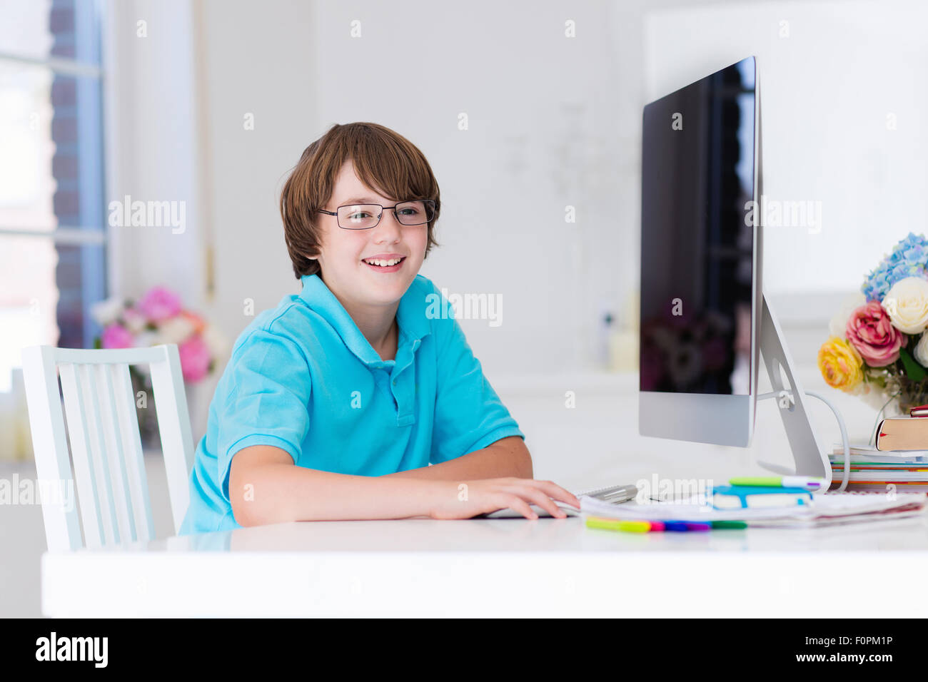 School boy working on personal computer at home. Student doing homework