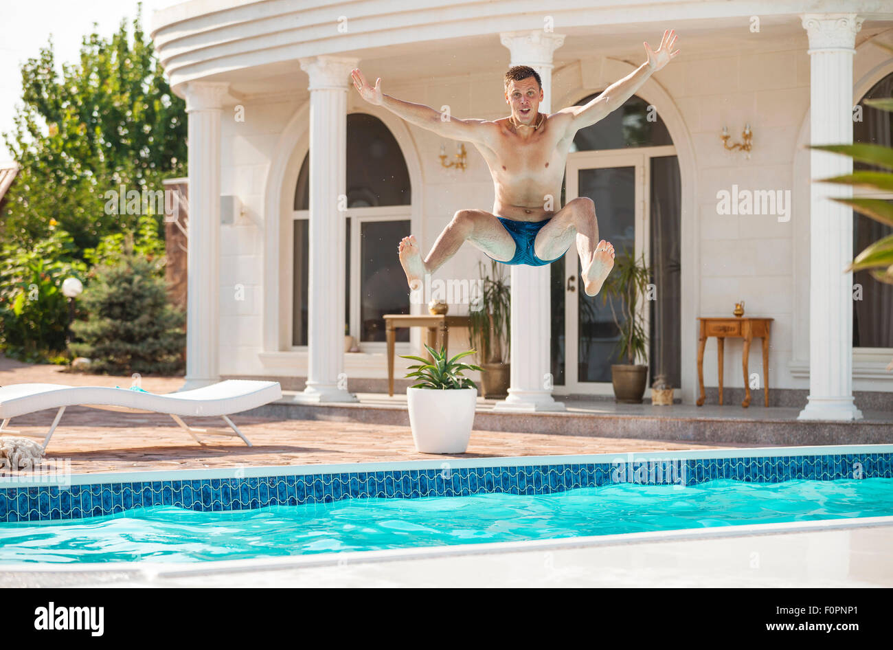 Happy young man jumping into the swimming pool Stock Photo