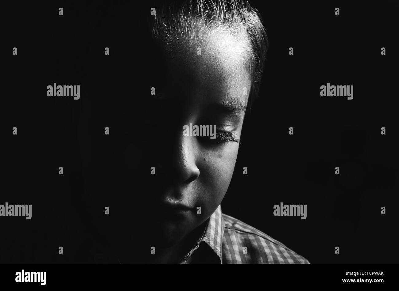 Black and white low key portrait of sad little boy Stock Photo