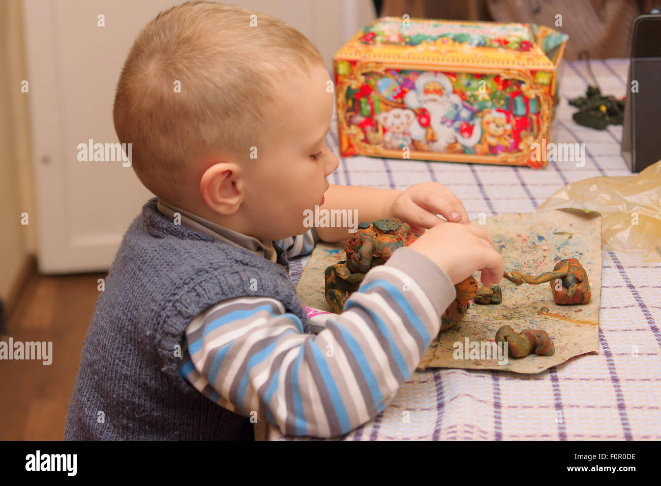 the little boy sits at a table and molds products from plasticine Stock Photo