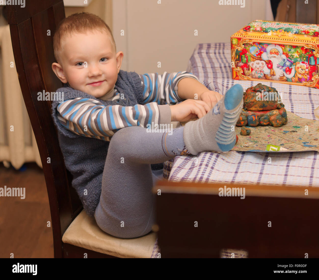 the little boy sits at a table and molds products from plasticine Stock Photo