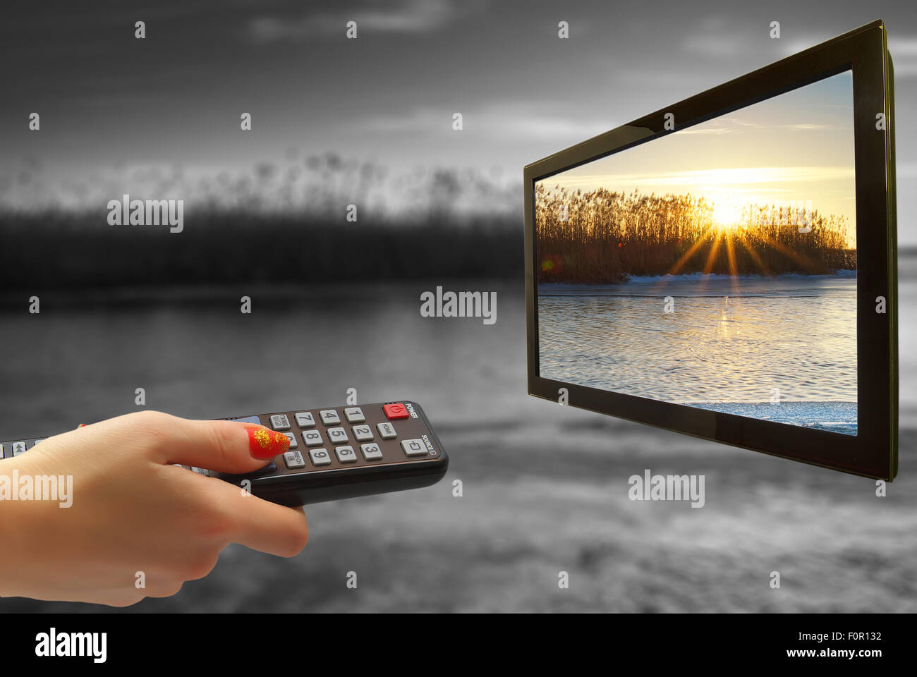 girl hand switches TV channels. Nature. Abstract. remote control in hand and TV Stock Photo