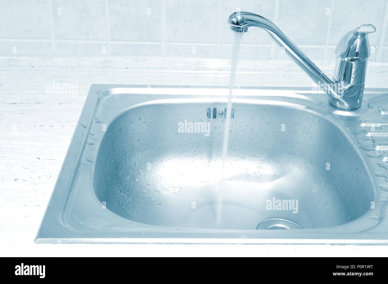Metallic kitchen sink with tap and water Stock Photo - Alamy