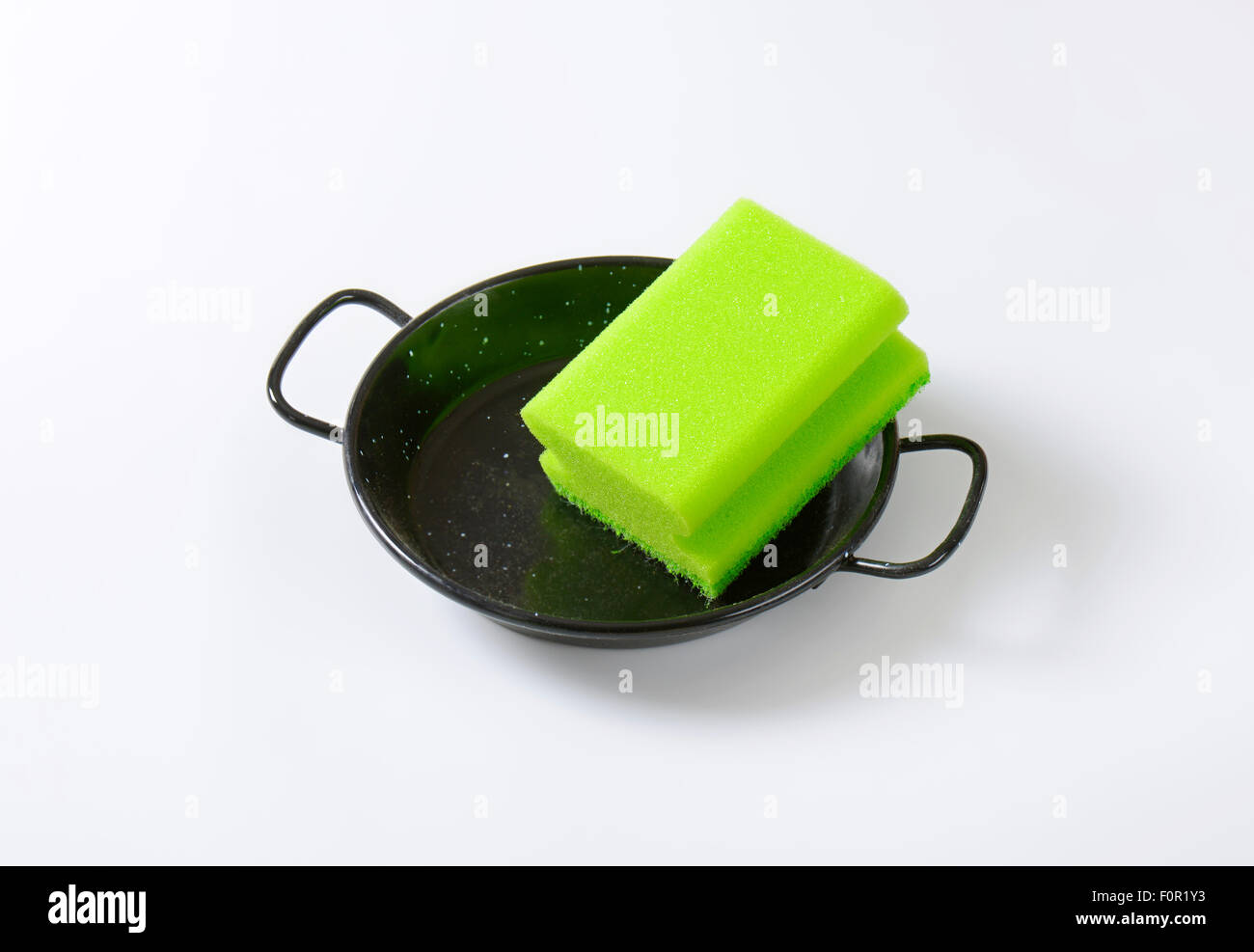 green kitchen sponge on black skillet Stock Photo - Alamy