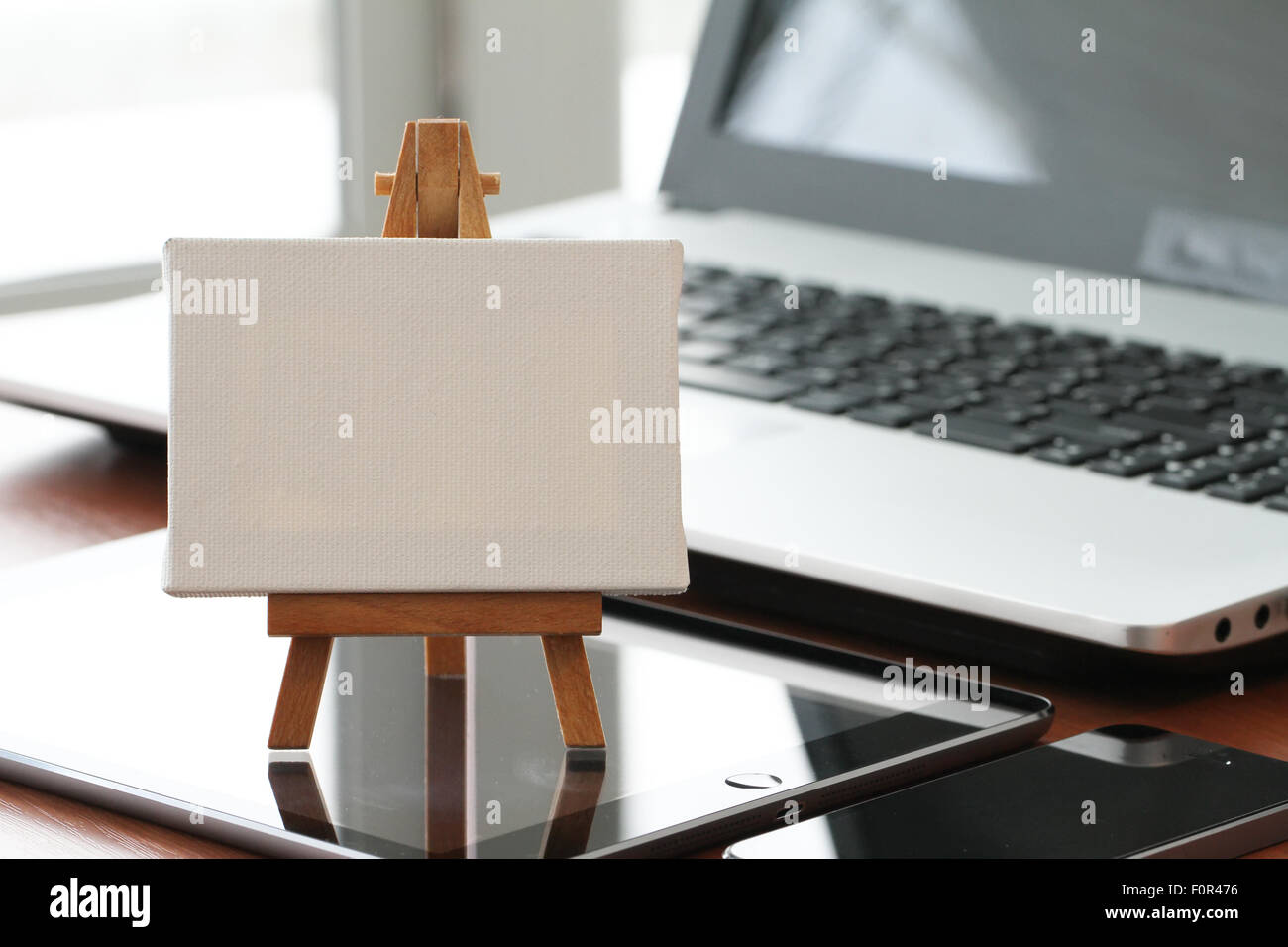blank canvas and wooden easel on laptop computer as concept Stock Photo