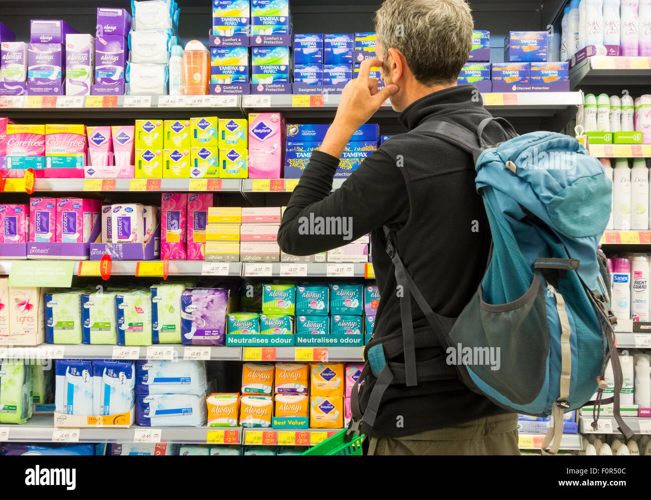 Middle aged man looking confused near feminine care products display in