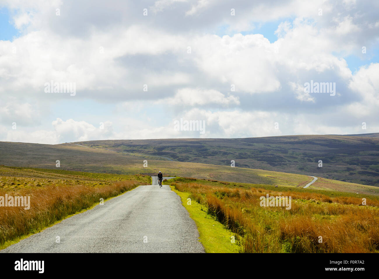 Female cyclist descending from Cross o’Greet on a high road across the Bowland Fells Lancashire Stock Photo