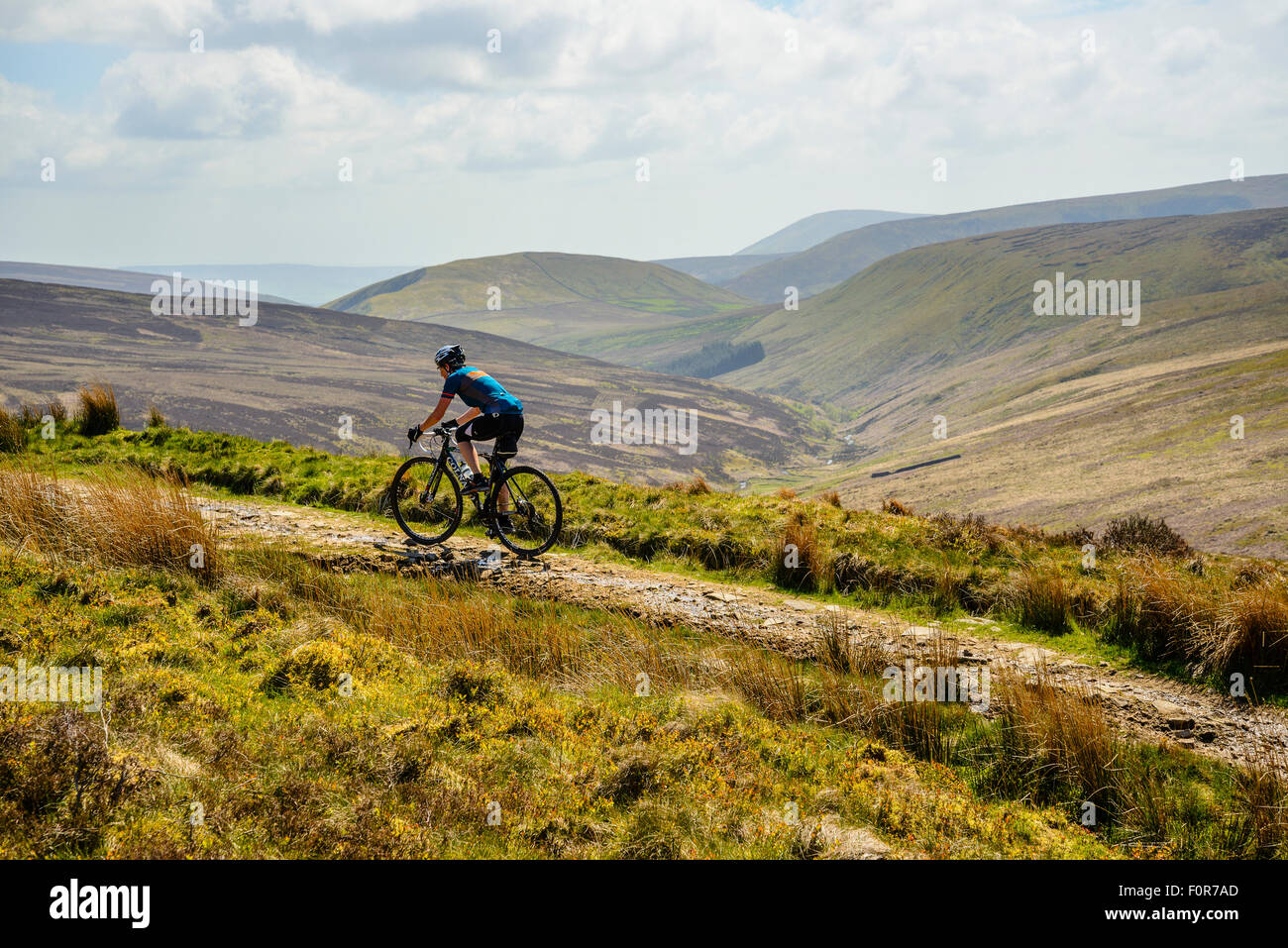 Female cyclist on a track across the Bowland Fells Lancashire variously known as Salter’s Way Salter Fell Road or Hornby Road Stock Photo