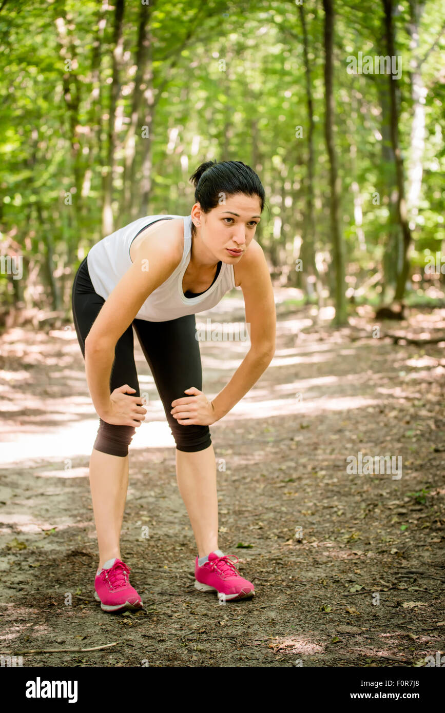 Tired young woman resting after jogging in nature Stock Photo