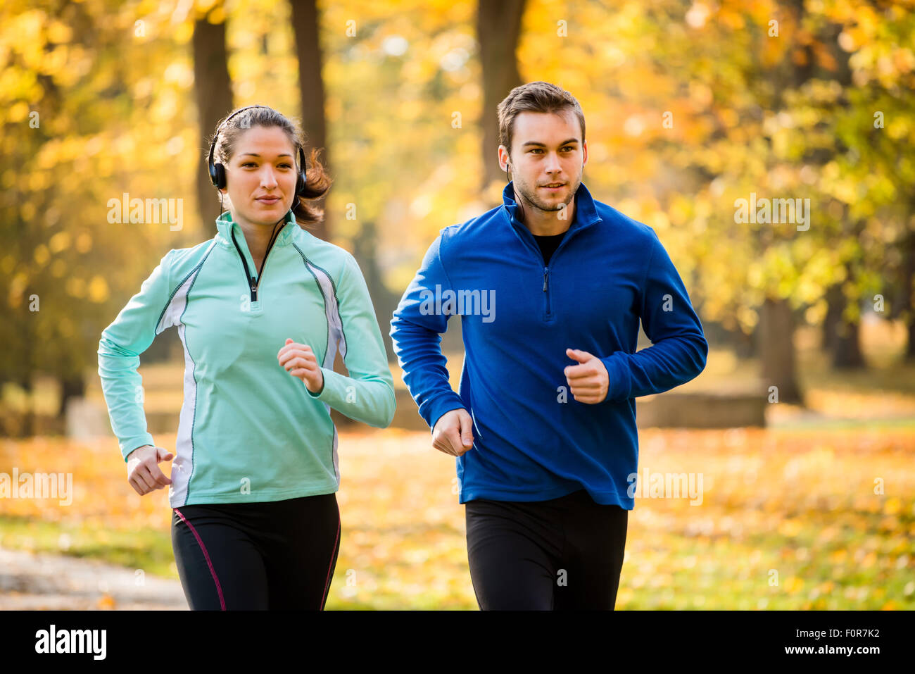 Couple jogging together in nature, woman listening music Stock Photo