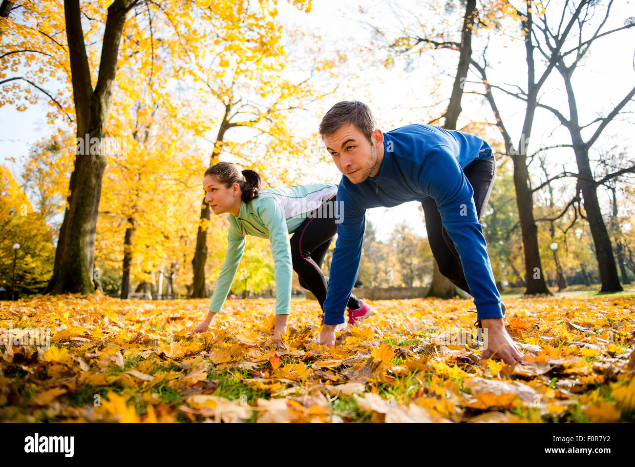 Young couple in steady position prepared for running in autumn nature Stock Photo
