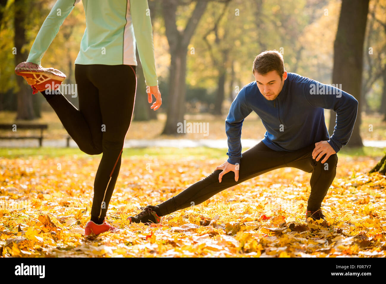 Young couple stretching legs before running in autumn nature Stock Photo