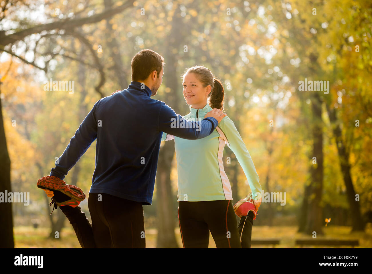 Young couple stretching legs before jogging in autumn nature Stock Photo
