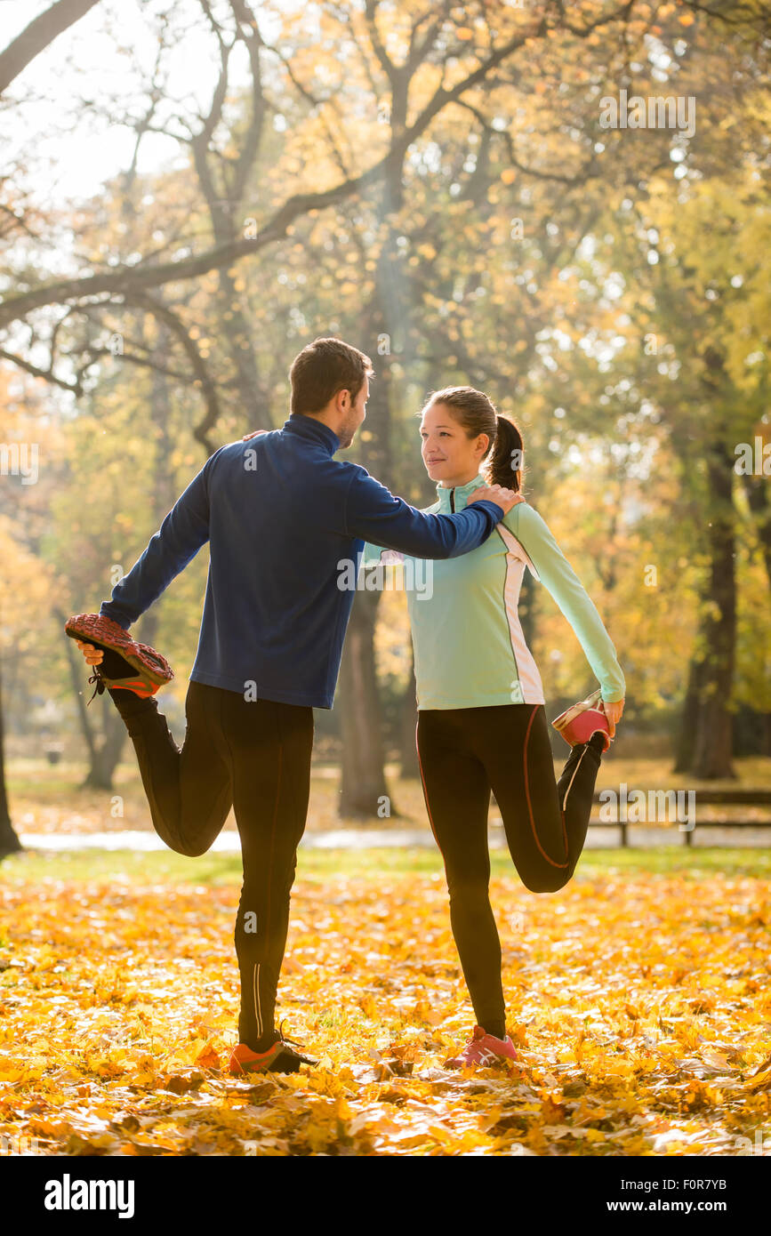 Young couple stretching legs before running in autumn nature Stock Photo